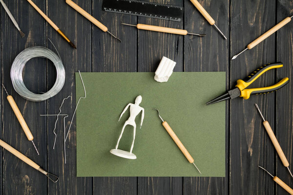 Craftsman workplace, ready for working on human sculpture. Sculpturing from polymer clay on working table with tools. Art craft concept, hobby or work process. Flat lay, top view