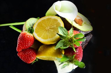 Siyah arka planda kalla çiçeği olan olgun egzotik meyveler seti, sağlıklı gıda konsepti. 