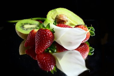 Siyah arka planda kalla çiçeği olan olgun egzotik meyveler seti, sağlıklı gıda konsepti. 