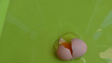 Yeşil kasede kırılan tavuk yumurtası, yakın görüş. 