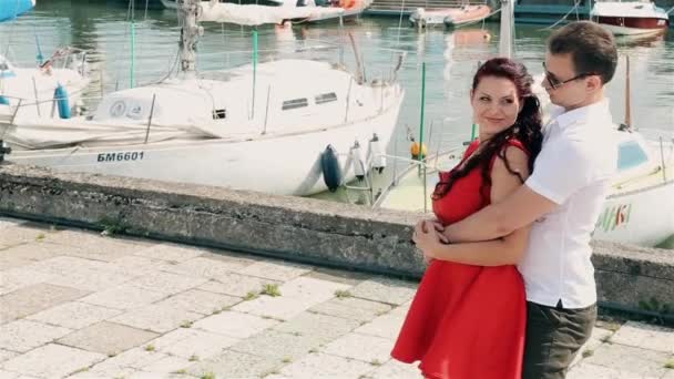 Un giovane ragazzo con passione ha preso la ragazza in un vestito rosso per la vita — Video Stock