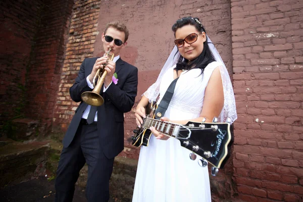 The groom plays the saxophone and the bride plays the electric guitar Stock Image