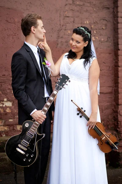 The groom plays the guitar and the bride plays the violin Stock Picture