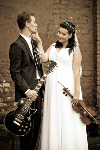 The groom stands with a guitar and the bride with a violin Stock Image