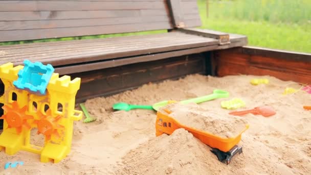 Un niño en el jardín de infantes jugando en el arenero con arena — Vídeos de Stock