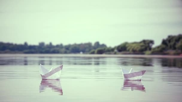 Две маленькие бумажные лодки, плавающие по воде — стоковое видео