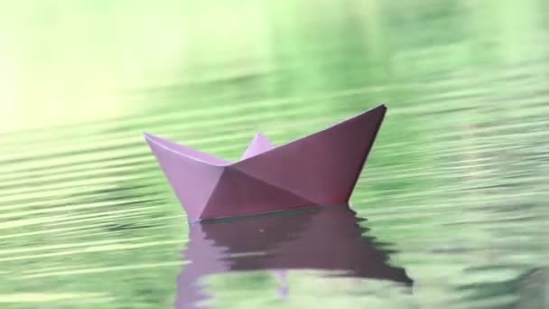 Три цветные бумажные лодки, плавающие по воде — стоковое видео