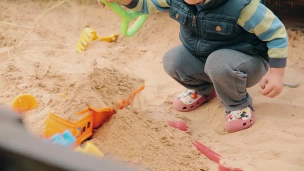Kind im Dorf spielt bei trübem Wetter im Sandkasten — Stockvideo