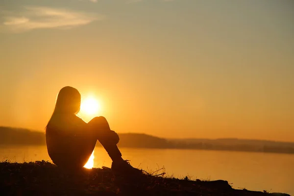 Adolescente sentada en la playa y viendo el atardecer — Foto de Stock