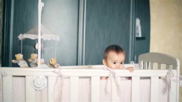 Маленька дівчинка стоїть в дерев'яному ліжку і солодко посміхається HD — стокове відео