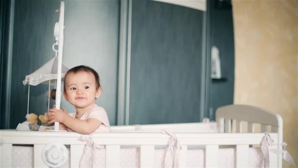 一个小女孩在婴儿床里涉足, 甜甜地微笑着 — 图库视频影像