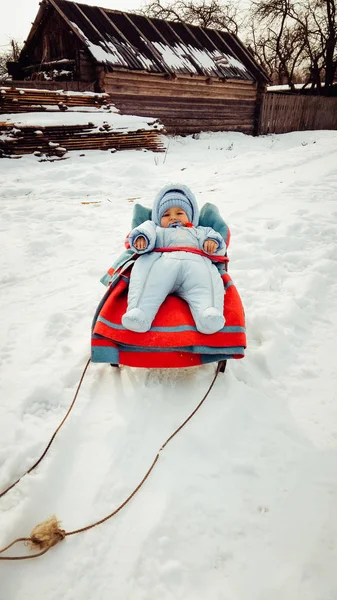 Das Baby liegt in einem Schlitten auf einer verschneiten Straße — Stockfoto