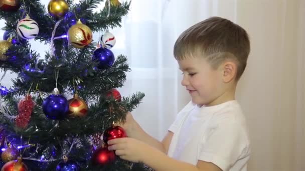 Un niño pequeño mira los juguetes del árbol de Navidad HD — Vídeos de Stock