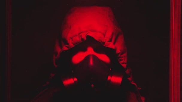 Ein Mann korrigiert die Maske in einem dunkelroten Raum. — Stockvideo