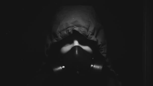 En man i kemiskt skydd och en gasmask är i ett mörkt rum — Stockvideo