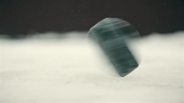 Snel close-up rotatie van een zwarte hockeypuck op een ijsbaan — Stockvideo