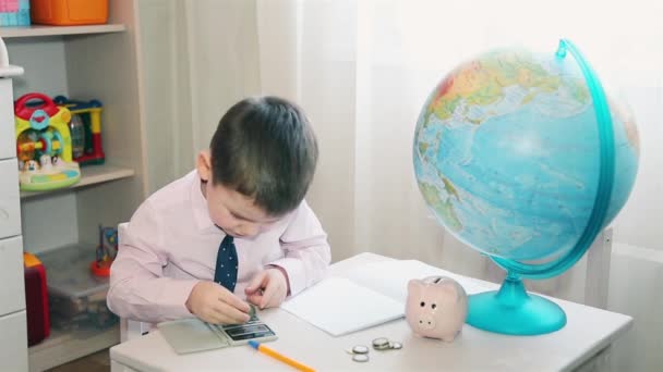 Маленький хлопчик рахує свої заощадження на калькуляторі HD — стокове відео