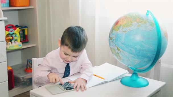 Niño cuenta sus ahorros en una calculadora — Vídeo de stock