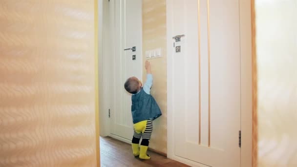 Een meisje met een tepel in haar mond staat op zijn tenen en schakelt u het licht in de badkamer en toilet — Stockvideo