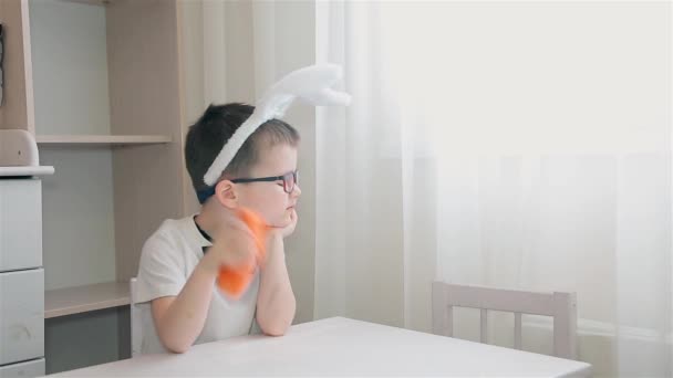 一个头上戴着兔子耳朵的男孩拒绝吃胡萝卜, 然后打了个喷嚏 — 图库视频影像