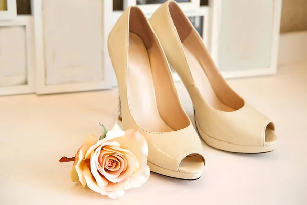 Beige shoes with high heels stand on the background of photo frames — Stock Photo, Image