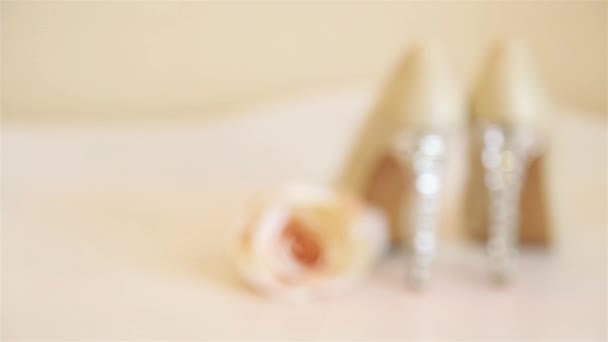 Scarpe da sposa con tacco alto poggiano su una cassettiera bianca con un bocciolo di rosa beige — Video Stock