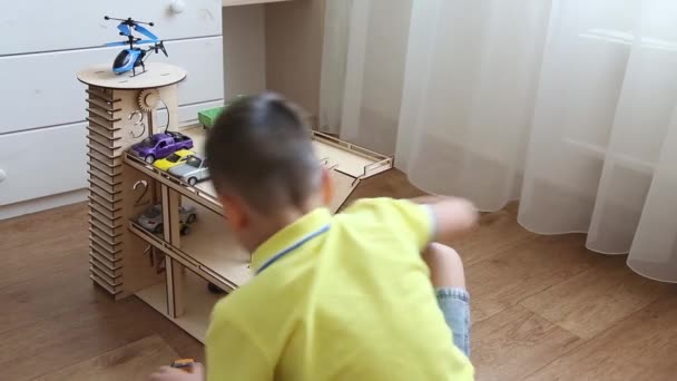 Niño preescolar jugando en la habitación de los niños con coches en el estacionamiento de madera — Vídeo de stock