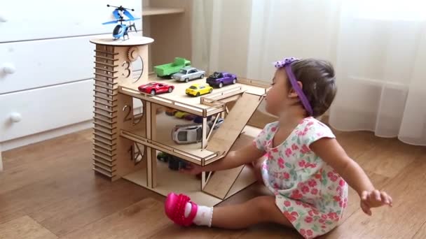 Petit enfant jouant à la maternelle dans le garage à jouets avec de petites voitures et hélicoptère HD — Video