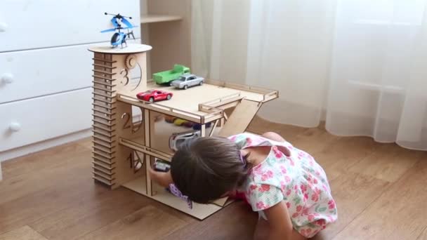 Bambina che gioca nella stanza dei bambini in un parcheggio in legno con piccole auto HD — Video Stock