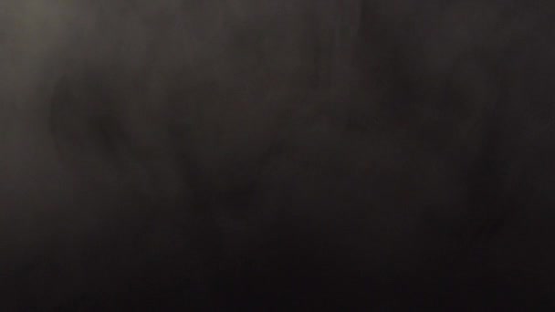 Rök sprider sig över ytan på en svart bakgrund — Stockvideo
