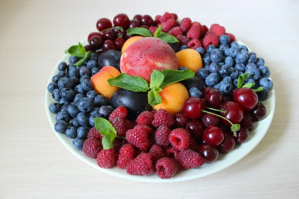 Mélange de baies d'été sur une assiette blanche sur fond clair. Texture ou fond — Photo