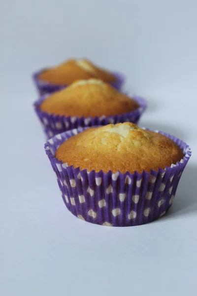 Drei Cupcakes in einer blauen Verpackung auf einem hellen Hintergrund. Textur oder Hintergrund — Stockfoto