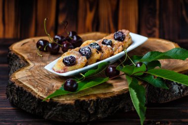 bir tabak ve ahşap bir tahta üzerinde yeşil yaprakları ile kiraz çilek kiraz soslu krep