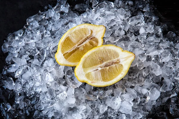 Lemon wedges with pieces of ice on black background