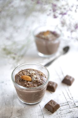 çiçeklerle süslenmiş hafif bir arka plan üzerinde Bademli çikolatalı puding