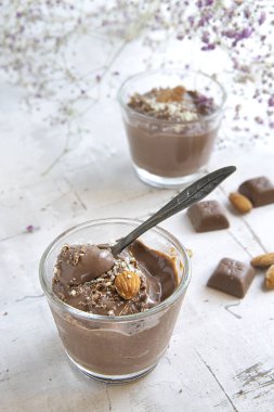 çiçeklerle süslenmiş hafif bir arka plan üzerinde Bademli çikolatalı puding