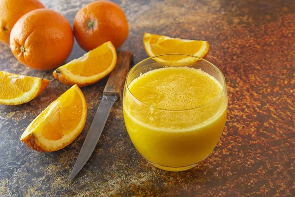 Sliced oranges and orange juice on the table. dark background.