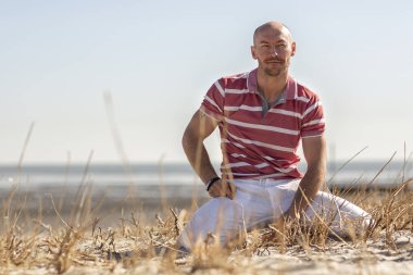  Denizcilik teması. Deniz turu. Kuzey denizi. Sahilde dinlenen genç bir adam. Almanya.