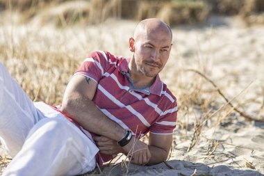  Denizcilik teması. Deniz turu. Kuzey denizi. Sahilde dinlenen genç bir adam. Almanya.