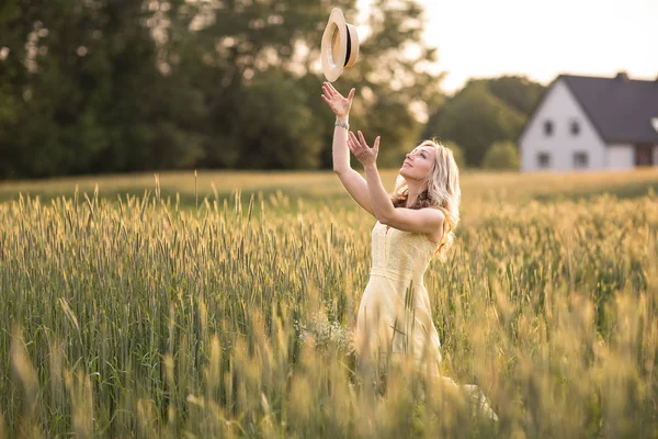 Coucher de soleil en été.Vie rurale.Une jeune femme sur le terrain jette un chapeau. Style rustique — Photo