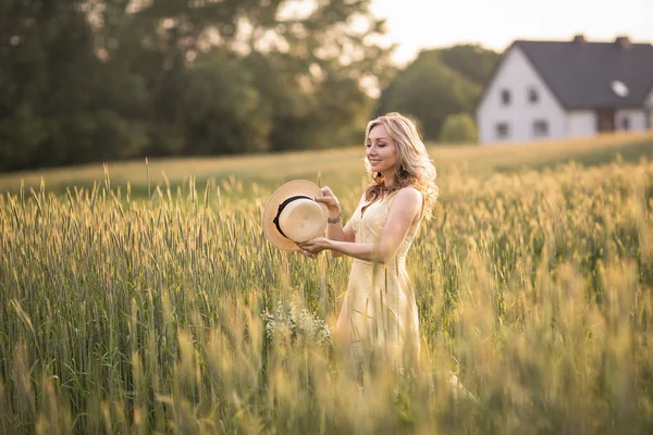 Solnedgång på sommaren. Landsbygdslivet. En ung kvinna på fältet kastar en hatt. Rustik stil — Stockfoto