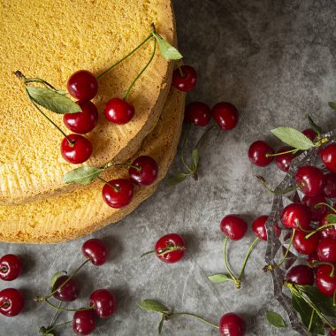 Koyu bir arka plan üzerinde kiraz çilek ile Bisküvi kek . Pişirme, kek kiraz monte etmek için sünger katmanları hazırlanması. tatil ve doğum günleri.yukarıdan görünümü