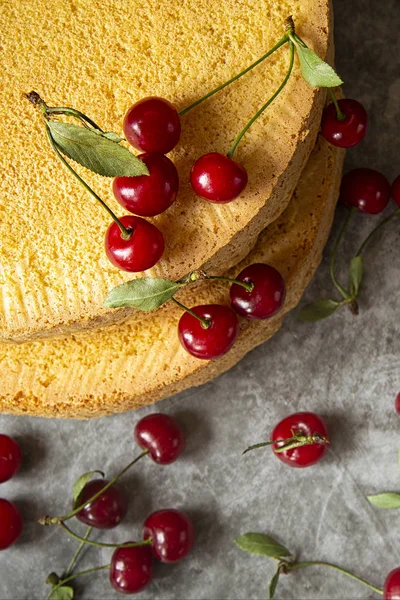 Bolos de biscoito com bagas de cereja em um fundo escuro. Cozimento, preparação de camadas de esponja para montar a cereja do bolo. feriados e aniversários.a vista do topo — Fotografia de Stock