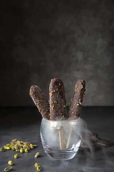 Chokladglass med pistagenötter på mörk bakgrund och med ånga. Sommarsäsong, varm sommar. Stockbild