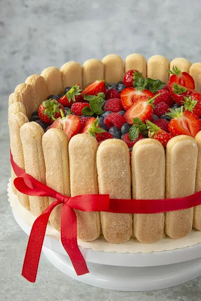 Bolo de baga decorado com grandes morangos, framboesas, mirtilos em um fundo leve. Doces festivos e mesa doce. Bagas de verão e sobremesas. Preparação de confeiteiros.savoiardi — Fotografia de Stock