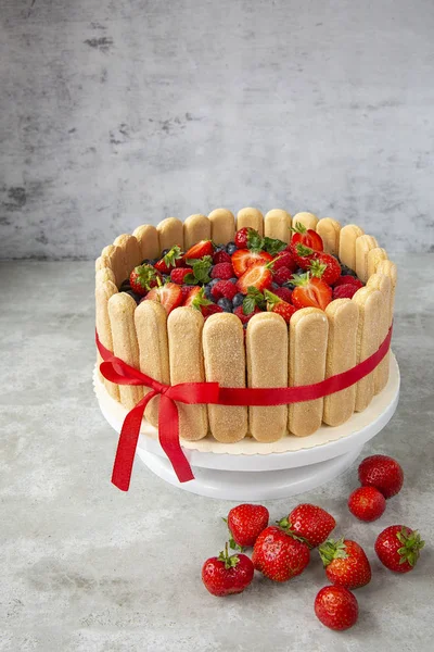 Bolo de baga decorado com grandes morangos, framboesas, mirtilos em um fundo leve. Doces festivos e mesa doce. Bagas de verão e sobremesas. Preparação de confeiteiros.savoiardi — Fotografia de Stock