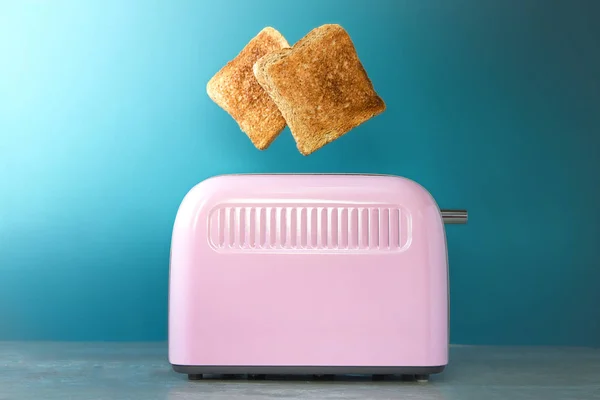 a pink toaster oven with leaping slices of fried bread on a blue background