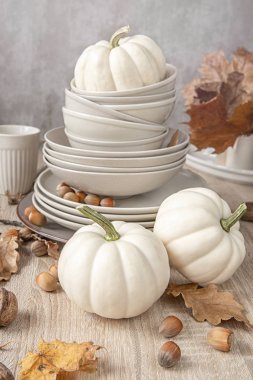 Masanın üzerinde farklı boyutlarda bir yığın beyaz balkabağı sonbahar yaprakları ve fındıkla süslenmiş. sonbahar