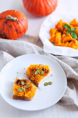 Yeşil, biber ve tohum ile püre kabak ile tost. Kavrulmuş kabak ile baharatlar serpilir beyaz parşömen üzerine dilimlenmiş. Açı görünümü natürmort üzerinde ahşap ve kumaş arka plan.