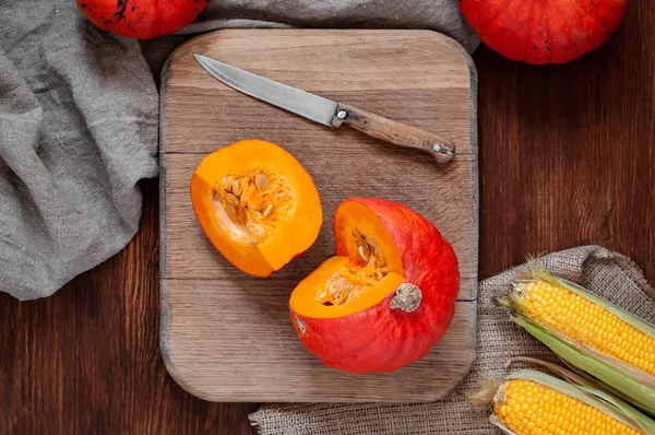 Dilimlenmiş ve bütün pumpkins, canvas kumaş ahşap zemin üzerine bıçakla kesme tahtası üzerinde Mısır. Üstten görünüm natürmort rustik tarzda sonbaharda hasat ile.